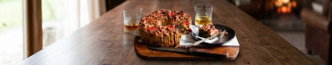 Bourbon and rum fruitcake with a slice and two tasting glasses on a rustic wooden table